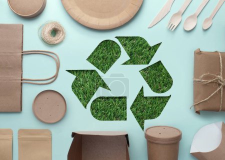 Foto de Papel cortado con hierba revelando el símbolo del reciclaje en medio de una colección de envases ecológicos con bajas emisiones de carbono - Imagen libre de derechos