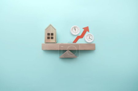 Téléchargez les photos : Maison miniature et signe de pourcentage avec des horloges équilibrées sur une scie à métaux - en image libre de droit