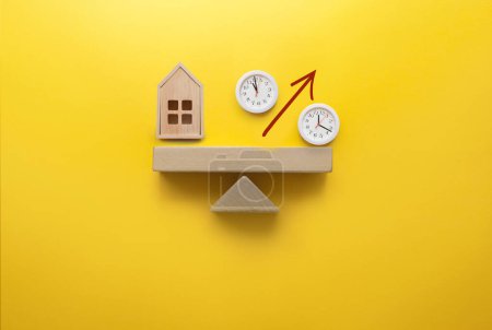 Foto de Casa en miniatura y signo de porcentaje con caras de reloj balanceadas en un balancín, inversión, hipoteca, decisión de tasa de interés - Imagen libre de derechos