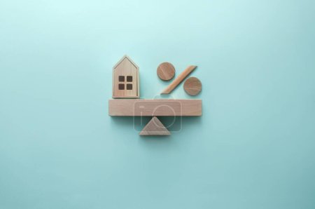 Foto de Casa en miniatura y signo de porcentaje equilibrado en un balancín - Imagen libre de derechos