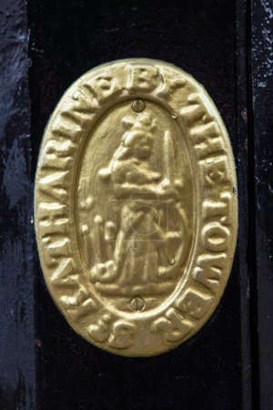 Nahaufnahme einer goldbemalten St. Katharine by the Tower, auf einem Laternenpfahl in den St. Katharine Docks in London, Großbritannien.