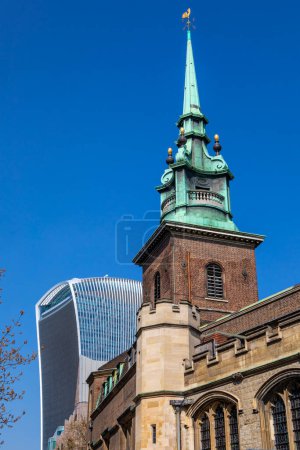 Die Turmspitze von All Hallows by the Tower - die älteste Kirche in der City of London, Großbritannien. Im Hintergrund der moderne Wolkenkratzer 20 Fenchurch Street, der als Walkie Talkie bekannt ist.