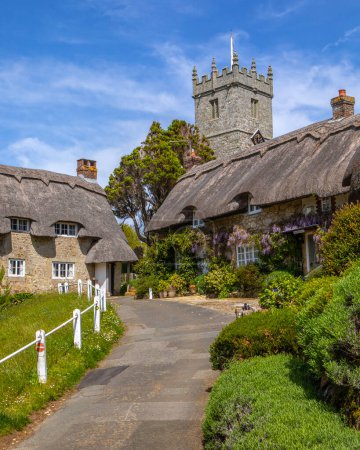 Der Turm der Allerheiligen-Kirche und schöne reetgedeckte Häuschen im malerischen Dorf Godshill auf der Isle of Wight, Großbritannien.