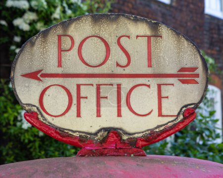 Großaufnahme eines alten Postamts-Schildes an einem roten Briefkasten im Zentrum Londons, Großbritannien.