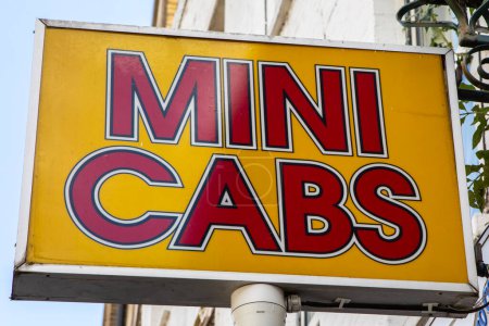 Close-up of a Mini Cabs sign on the exterior of a building in the UK.