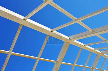Téléchargez les photos : Structure métallique faite de tuyaux carrés et rectangulaires sur fond de ciel sans nuages - en image libre de droit