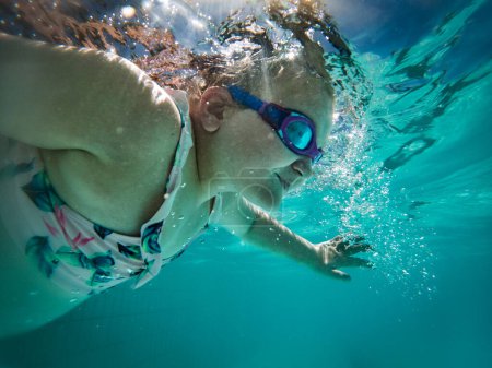 Foto de Una joven nadadora talentosa se sumerge en un grupo de torneos de tamaño completo para entrenar o competir. - Imagen libre de derechos