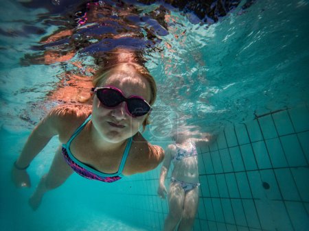 Photo for A talented young girl swimmer dives into a full-size tournament pool to train or compete. - Royalty Free Image