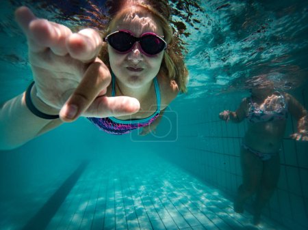 Foto de Una joven nadadora talentosa se sumerge en un grupo de torneos de tamaño completo para entrenar o competir. - Imagen libre de derechos