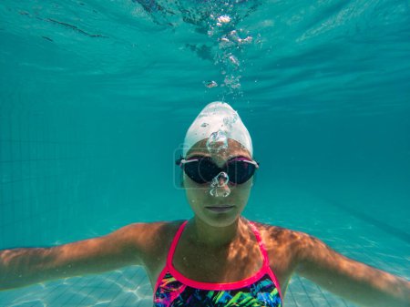 Foto de Una talentosa nadadora se sumerge en un grupo de torneos de tamaño completo para entrenar o competir. - Imagen libre de derechos