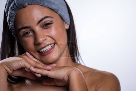 Photo for A stunning young woman takes care of her skin and beauty with a daily routine. Shot in a studio on a white background, her natural beauty radiates. - Royalty Free Image