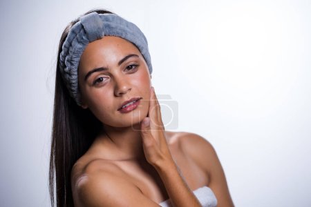 Photo for A stunning young woman takes care of her skin and beauty with a daily routine. Shot in a studio on a white background, her natural beauty radiates. - Royalty Free Image