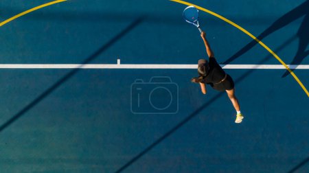 Téléchargez les photos : Vue aérienne d'une jeune joueuse de tennis en action sur un tout nouveau terrain. Cette photo a été prise avec un drone pour donner une perspective unique sur le jeu. - en image libre de droit