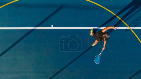Foto de Vista de pájaro de una joven jugadora de tenis en acción en una cancha nueva. Esta foto fue capturada con un dron para dar una perspectiva única sobre el juego. - Imagen libre de derechos