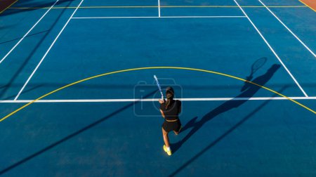 Foto de Vista de pájaro de una joven jugadora de tenis en acción en una cancha nueva. Esta foto fue capturada con un dron para dar una perspectiva única sobre el juego. - Imagen libre de derechos