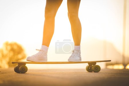 Téléchargez les photos : Jeune femme avec des cheveux foncés skateboard dans un environnement urbain dynamique. - en image libre de droit