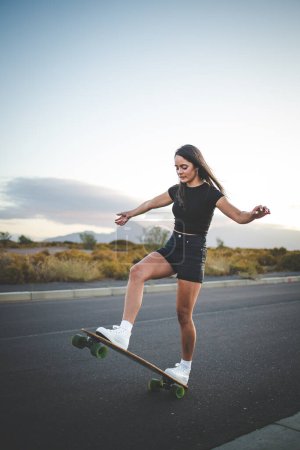 Photo for Pretty young woman with dark hair skateboarding in a vibrant urban environment. - Royalty Free Image