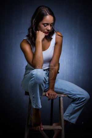 Photo for Pretty dark haired girl posing for a fashion shoot in a studio. She is dressed in stylish jeans and a crop top, and her poses convey a sense of youthfulness and vitality. - Royalty Free Image