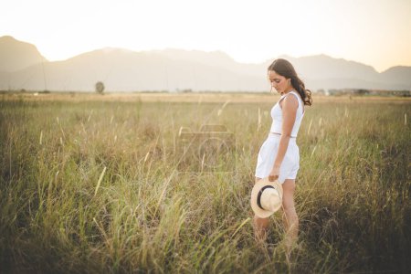 Téléchargez les photos : Belle jeune femme aux longs cheveux foncés dans un champ d'herbe haute. - en image libre de droit