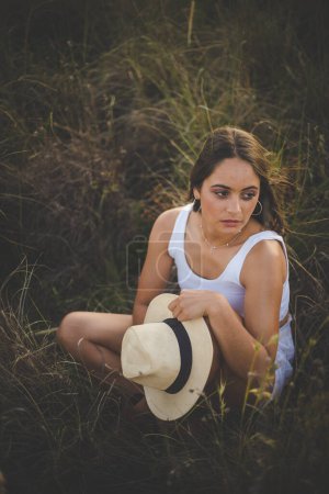 Photo for Beautiful young woman with long dark hair in a field of tall grass. - Royalty Free Image