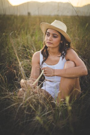 Foto de Hermosa joven con el pelo largo y oscuro en un campo de hierba alta. - Imagen libre de derechos