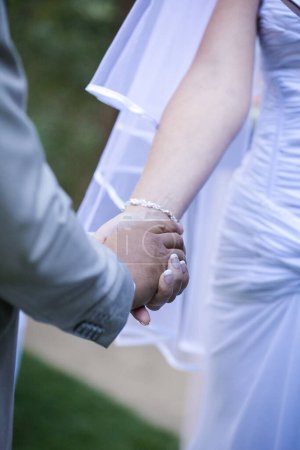 Photo for This beautiful image captures the intimate moment of a couple exchanging wedding rings at a real wedding. The photograph features a close-up of the couple's hands, showcasing their intertwined fingers and the wedding bands on their fingers. The image - Royalty Free Image
