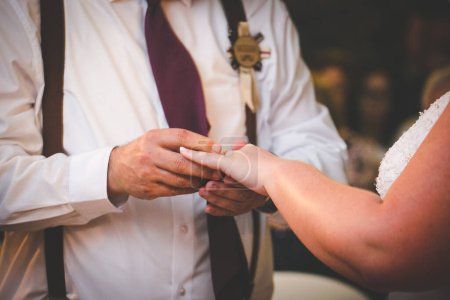 Photo for This beautiful image captures the intimate moment of a couple exchanging wedding rings at a real wedding. The photograph features a close-up of the couple's hands, showcasing their intertwined fingers and the wedding bands on their fingers. The image - Royalty Free Image