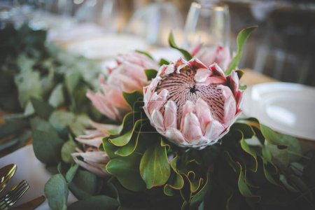 Foto de Esta cautivadora imagen muestra la decoración elegante y los impresionantes arreglos florales de una boda real. La fotografía presenta una mesa bellamente decorada en un encantador lugar de bodas, adornada con delicadas flores, velas y otros elementos decorativos - Imagen libre de derechos