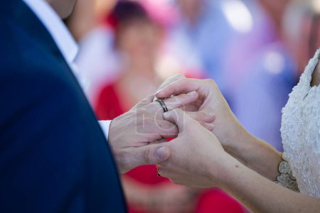 Foto de Esta hermosa imagen captura el momento íntimo de una pareja intercambiando anillos de boda en una boda real. La fotografía muestra un primer plano de las manos de la pareja, mostrando sus dedos entrelazados y las bandas de boda en sus dedos. La imagen - Imagen libre de derechos