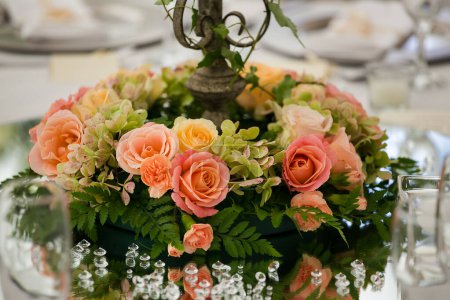 Foto de Esta cautivadora imagen muestra la decoración elegante y los impresionantes arreglos florales de una boda real. La fotografía presenta una mesa bellamente decorada en un encantador lugar de bodas, adornada con delicadas flores, velas y otros elementos decorativos - Imagen libre de derechos