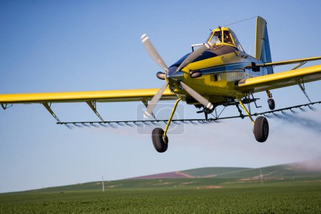 Téléchargez les photos : Image rapprochée d'un avion pulvérisateur pulvérisant des cultures céréalières sur un champ d'une ferme - en image libre de droit