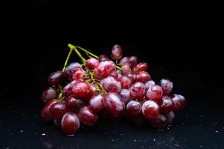 Uvas rojas frescas en uvas rosadas de fondo oscuro