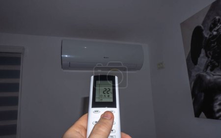 Arad,Romania 03 13 2024: Air conditioner inside the room operating remote controller. Air conditioner with remote controller