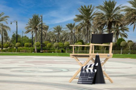 Photo for Director Chair, Movie Clapper and Megaphone on an Empty City Street with Palm Trees extreme closeup. 3d Rendering - Royalty Free Image