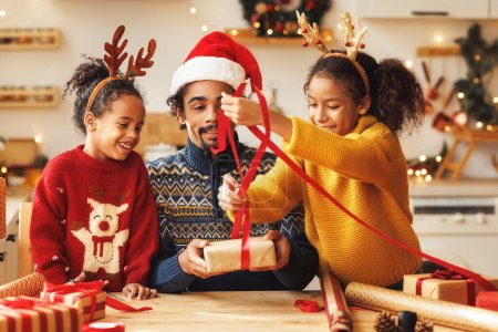 Téléchargez les photos : Heureux afro-américain famille père et enfants fille et fils pack cadeaux de Noël - en image libre de droit