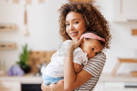 Photo for Happy, cheerful african american mother holds a laughing baby daughter in her arms. Concept of motherhood and a loving family - Royalty Free Image