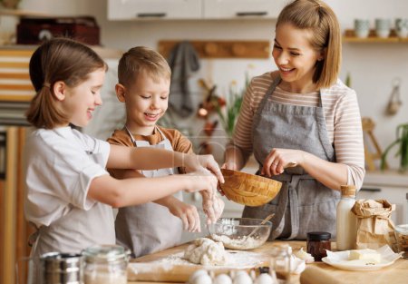 Photo for Content loving mother and cute kids: son and daughter adding ingredients in bowl and preparing dough at table at home - Royalty Free Image