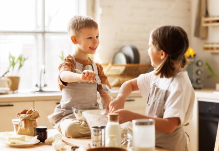 Photo for Happy children brother and sister making dough   while cooking together in cozy decorated kitchen, smiling boy and girl mixing ingredients for homemade xmas gingerbreads - Royalty Free Image