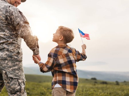 Téléchargez les photos : Vue arrière de l'homme militaire père tenant la main de son fils avec le drapeau américain et profitant d'une vue incroyable sur la nature en été le jour ensoleillé, heureux soldat papa réuni avec son fils après l'armée américaine - en image libre de droit