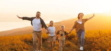 Foto de Familia feliz: madre, padre, hijos hijo e hija corriendo en la naturaleza al atardecer - Imagen libre de derechos
