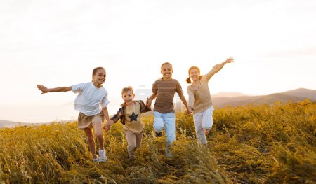 Photo for Group of happy joyful school kids   running and holding hands in field on sunny spring day, excited children   boys and girls enjoying summer holidays in countryside - Royalty Free Image
