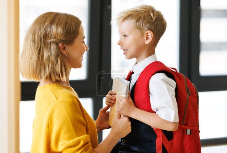 Photo for First day at school. Mother adjusts the briefcase to her happy son  during the  preparing   for school studies  at home - Royalty Free Image