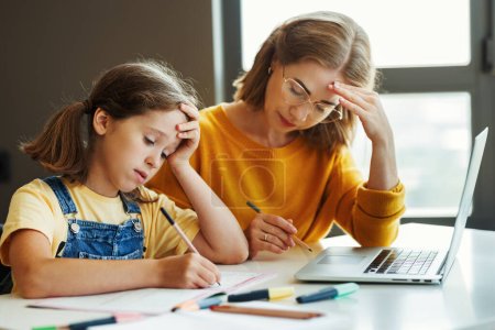 Photo for Frustrated teacher or mother and stressed schoolgirl browsing laptop while doing assignment together and studying remotely at home - Royalty Free Image