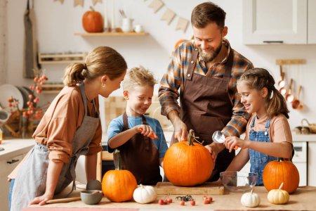 Photo for Happy family mother, father  and children daughter and son to remove   pulp from pumpkin while carving jack o lantern with family in cozy kitchen at home, parents with kids preparing for Halloween - Royalty Free Image