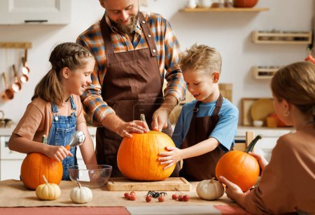 Photo for Happy family mother, father  and children daughter and son to remove   pulp from pumpkin while carving jack o lantern with family in cozy kitchen at home, parents with kids preparing for Halloween - Royalty Free Image
