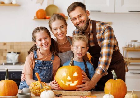 Foto de Feliz familia madre, padre e hijos sonriendo a la cámara hacen jack-o-linterna de calabaza durante la celebración, preparándose para Halloween - Imagen libre de derechos