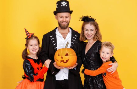 Photo for Cheerful family mother father and children in carnival costumes celebrate Halloween on colored yellow background - Royalty Free Image