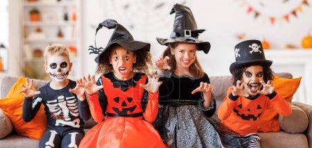 Foto de Feliz Halloween. Niños alegres en trajes de carnaval y maquillaje doung gestos de miedo en casa en casa durante las vacaciones - Imagen libre de derechos