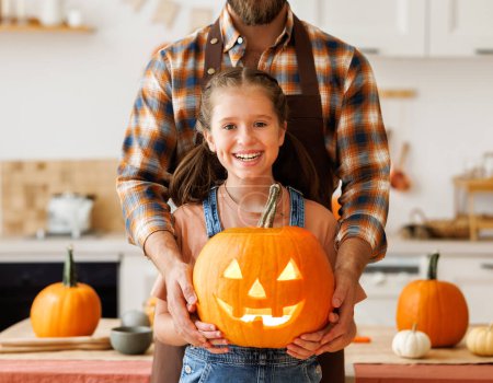 Photo for Cute happy   girl helping his father to carve Halloween pumpkin   at home and preparing for autumn holiday, family daughter and dad making Jack-o-Lantern together - Royalty Free Image