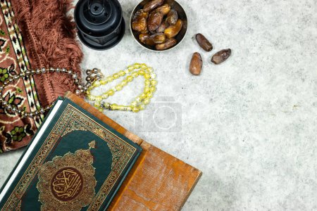 Foto de Linterna y Sagrado Corán con caligrafía árabe significado de Al Corán y alfombra de oración, rosario musulmán y dátiles frutos - Imagen libre de derechos